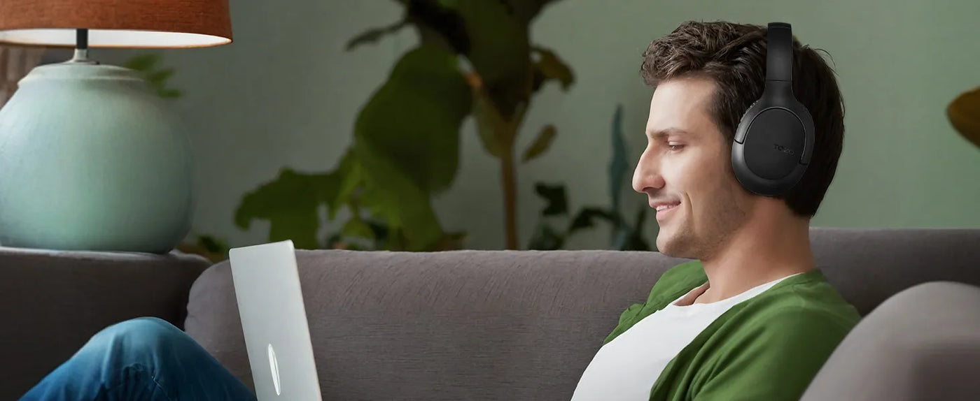 Man relaxing on sofa with TOZO H100 headphones